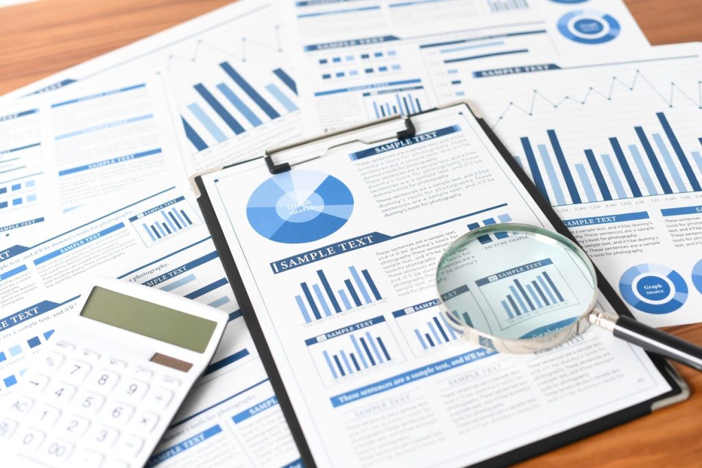 調査レポートと電卓と虫眼鏡
