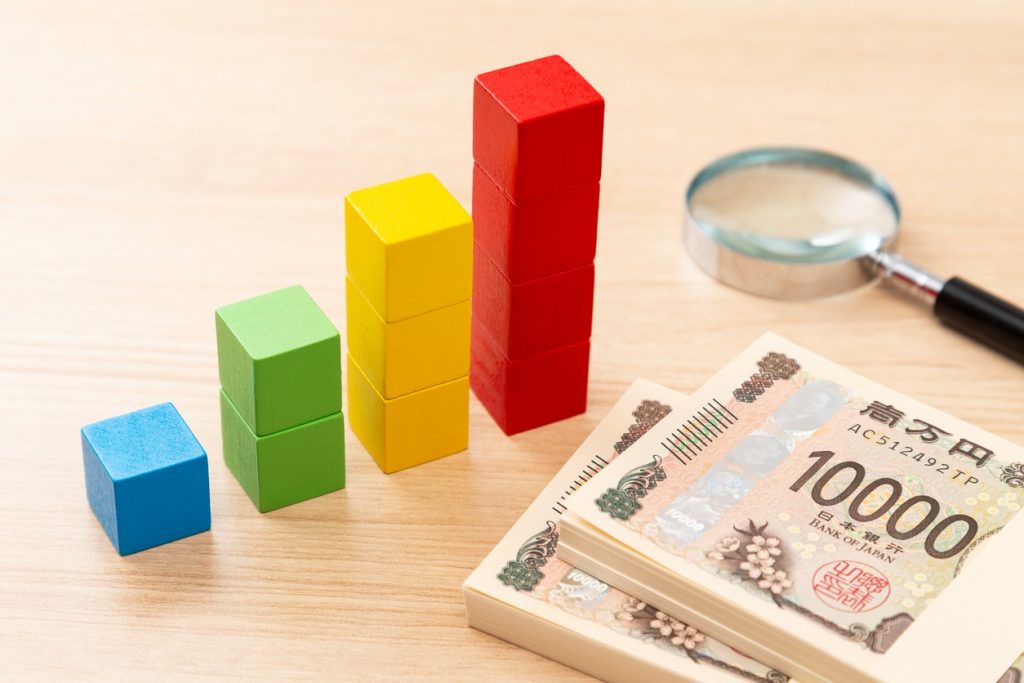 グラフとお金と虫眼鏡がおいてあるイメージ図
